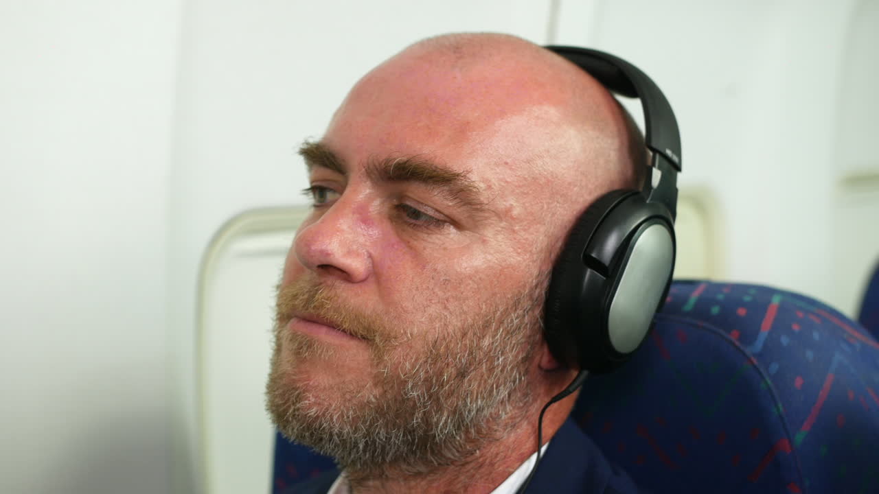 hombre feliz con auriculares escuchando música en un avión de pasajeros asintiendo con la cabeza