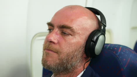 happy man wearing headphones listening to music on a passenger airliner plane nodding head