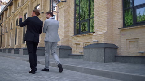 Back-view-business-people-talking-on-street.-White-collar-men-walking-to-work.