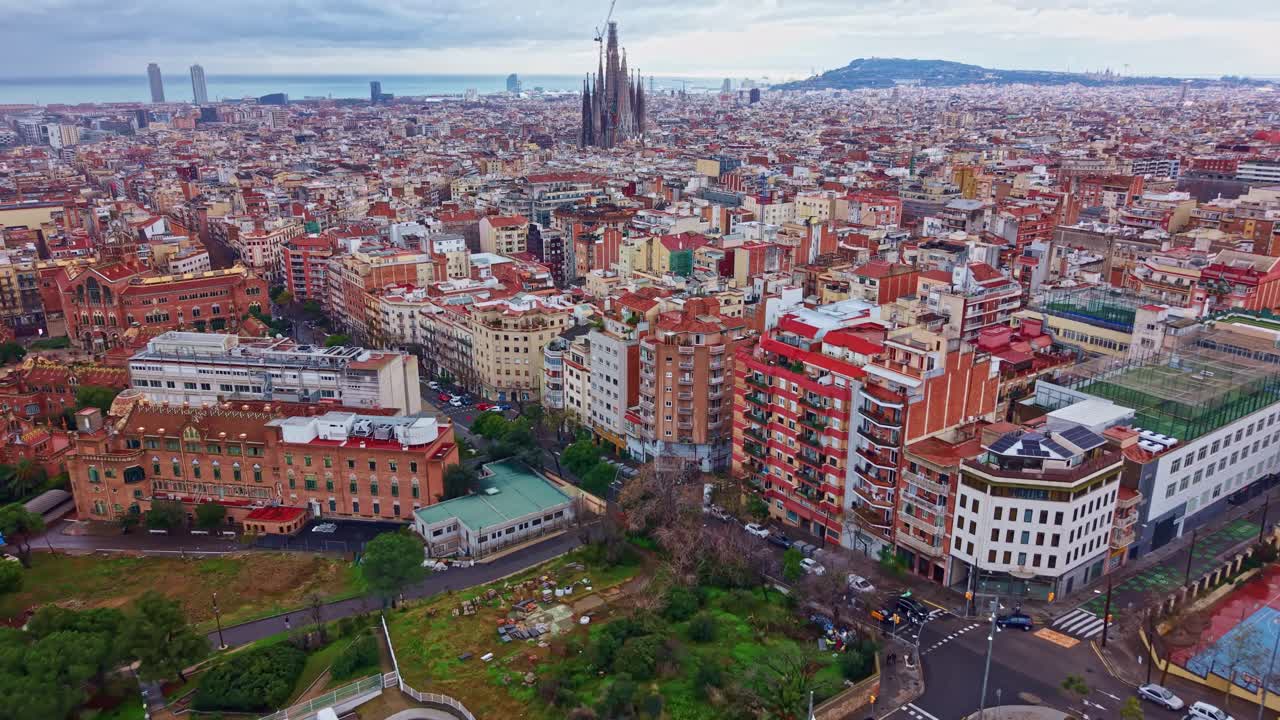 Quartiere Eixample e skyline urbano con l'iconica Sagrada Família a Barcellona, Spagna. Ripresa aerea all'indietro