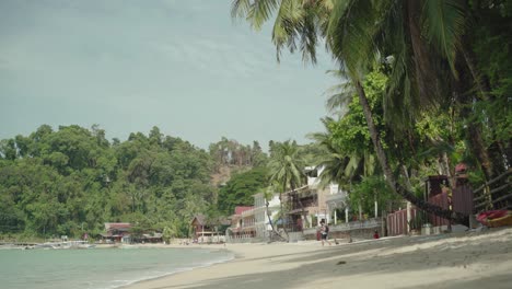 Turista-Caminando-Por-La-Playa-Tropical-En-El-Nido,-Filipinas,-Que-Se-Compone-De-árboles-Exóticos-Y-Arena-Blanca-Durante-El-Día-Soleado---Perfecto-Para-Las-Vacaciones-De-Verano---Plano-General