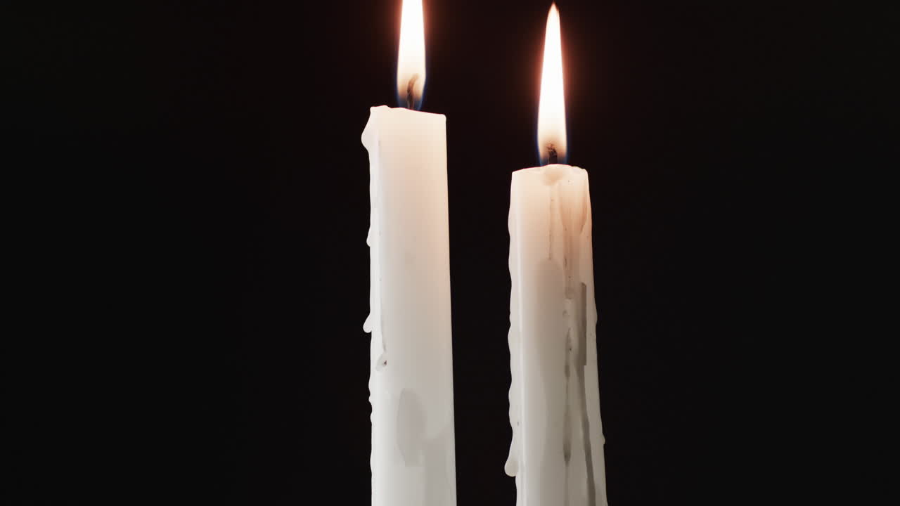 Video di due candele bianche con fiamma bianca e spazio per il testo su sfondo nero