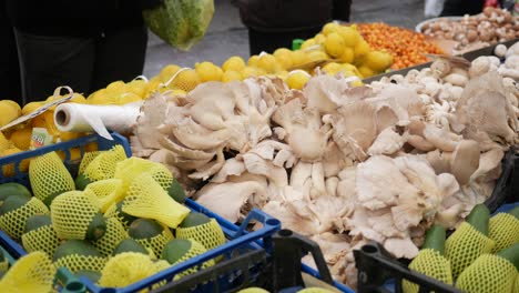 a vibrant street market with a variety of fresh produce, including mushrooms, avocados, and lemons.