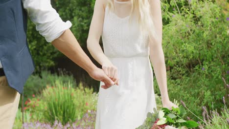 coppia felice e diversificata che cammina in giardino in un giorno di sole al matrimonio