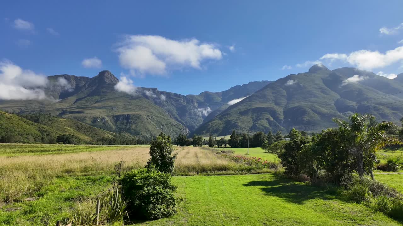 Giornata luminosa e soleggiata in una fattoria a Swellendam, Sudafrica, con nuvole che si muovono sulle montagne Langeberg