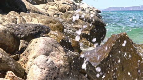 slow motion shot of waves splashing at rocks, sesi beach, attica , greece