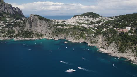 pleasure craft enjoying azure waters off rugged capri, italy