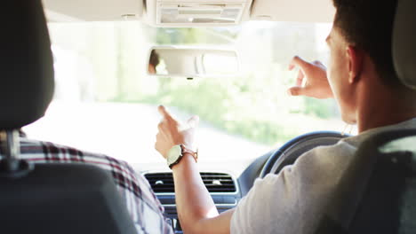 african american father instructing son about rear view mirror before driving lesson, slow motion