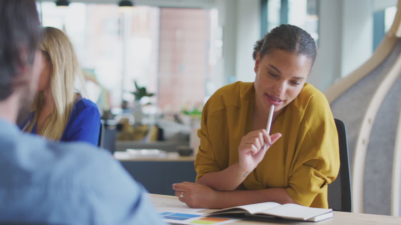 Business Team Having Meeting Sitting Around Table Making Notes In Modern Open Plan Office