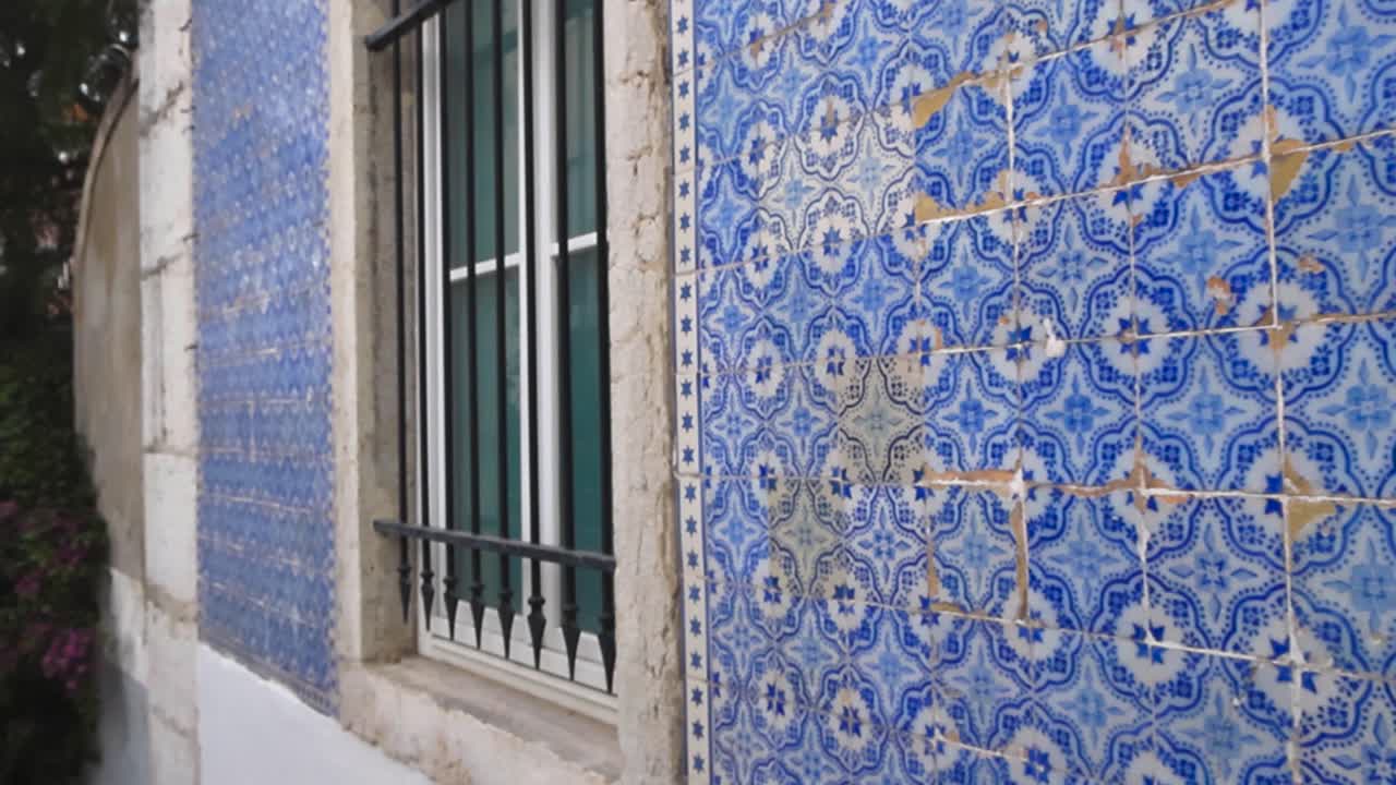 Vista cinematografica diurna delle tradizionali piastrelle in ceramica azulejo blu su una parete di un edificio di Lisbona con profondità di campo ridotta e un leggero movimento della fotocamera