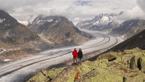 couple hiking in norway mountains with golden retriever and scenic glacier view