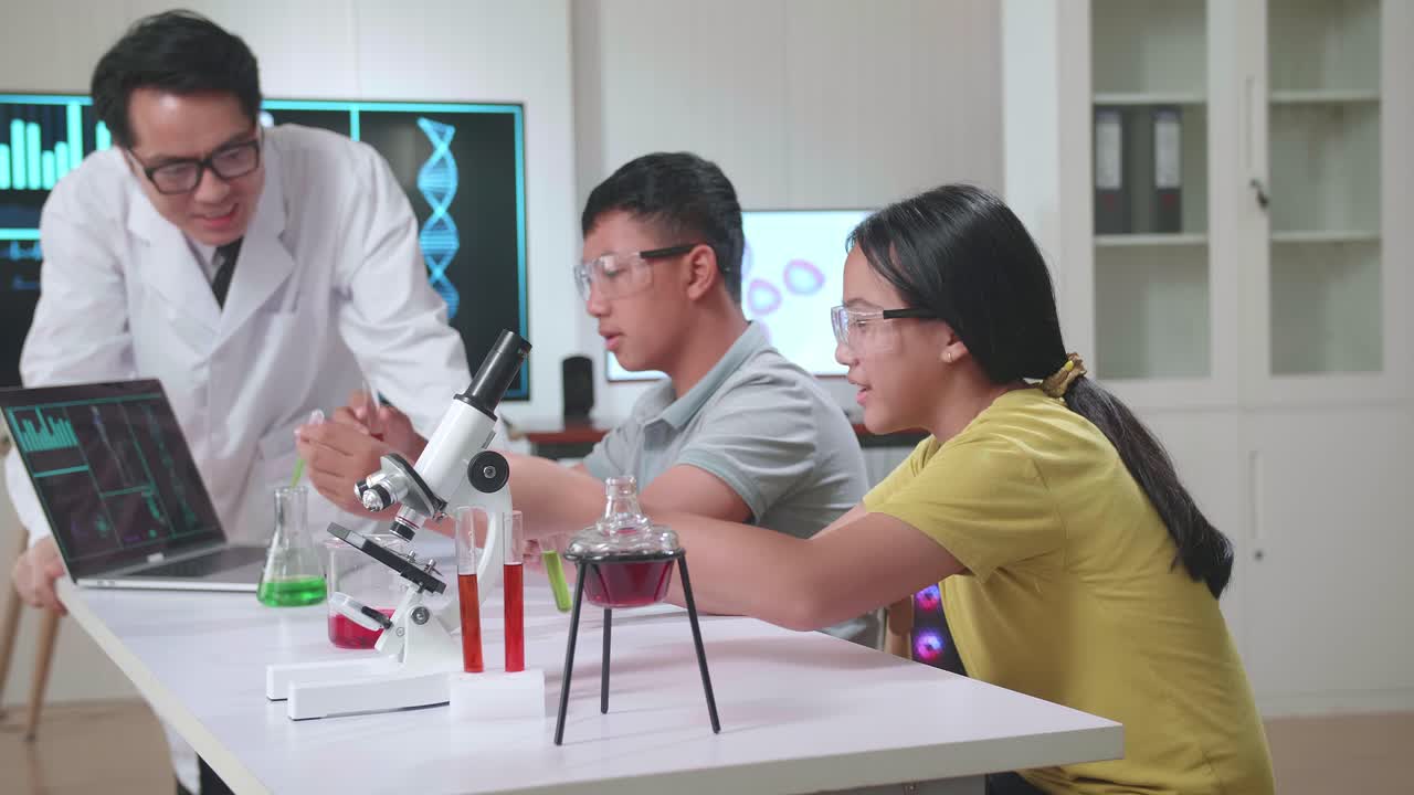 Excited Young Asian Boy And Girl Learning Science Experiment In Laboratory With Teacher In Classroom. Study With Scientific Equipment And Test Tubes