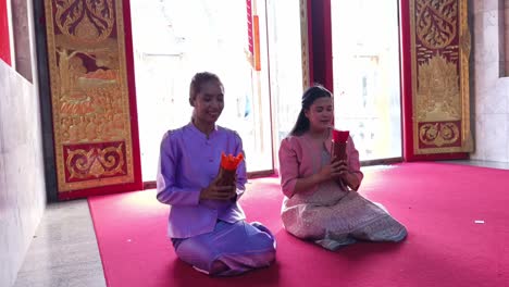 two women in traditional thai clothing at a temple