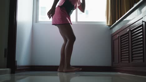 woman in pink pajamas jumping in a bathroom