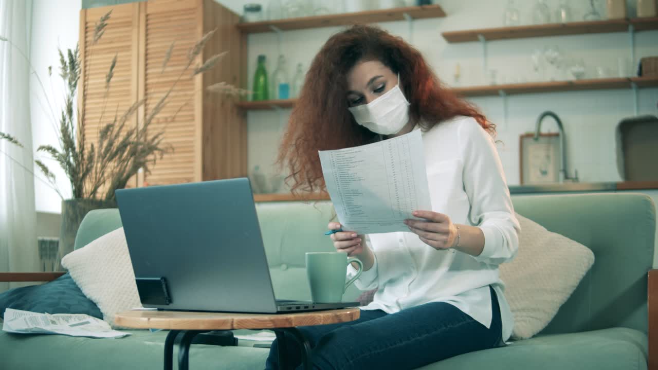 Lavoro da casa durante la pandemia di COVID-19. Una donna con la mascherina lavora da casa in quarantena.