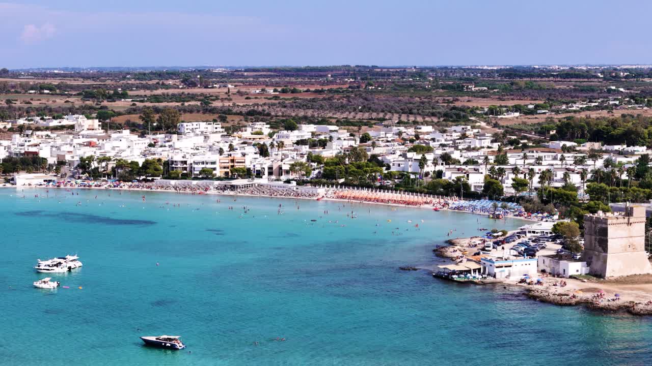 Touristic sandy beach with bed and umbrella near white town, aerial view