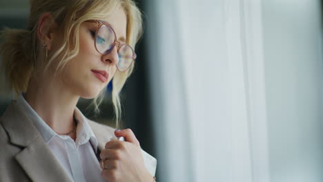 una mujer de negocios triste y desanimada está de pie junto a la ventana.