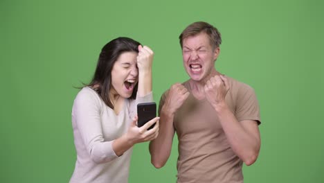 young happy couple using phone while looking excited together