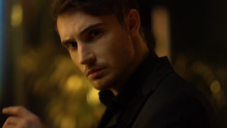 sensual guy thinking in dark background. focused man touching face indoors.