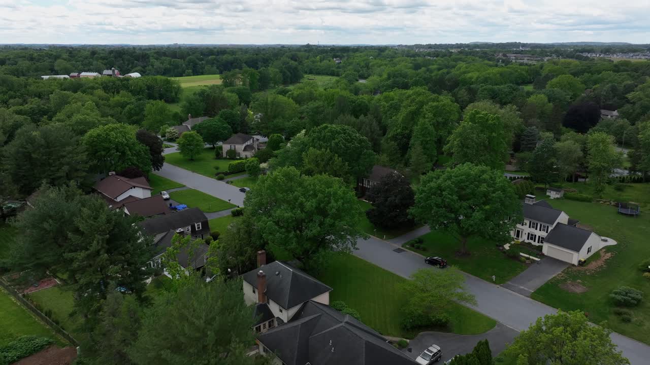 Quiet noble neighborhood in America with swimming pools in garden. Summer da. With green trees along streets. Suburb district of city in United States. Aerial flyover shot.