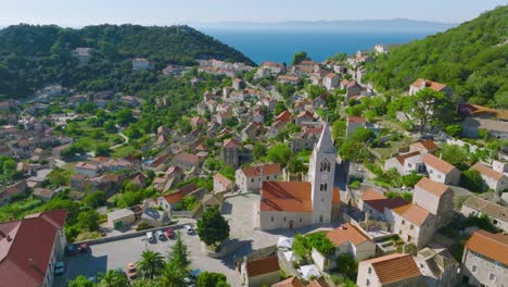 vista aérea sobre la torre de la iglesia del pueblo en la isla lastovo en croacia - disparo de drones