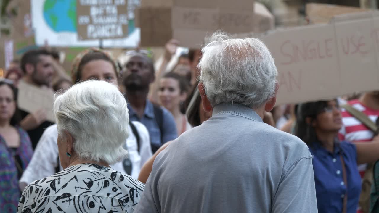 Senior Couple Watching Protesters on March Against Climate Change in Barcelona, Catalonia, Spain