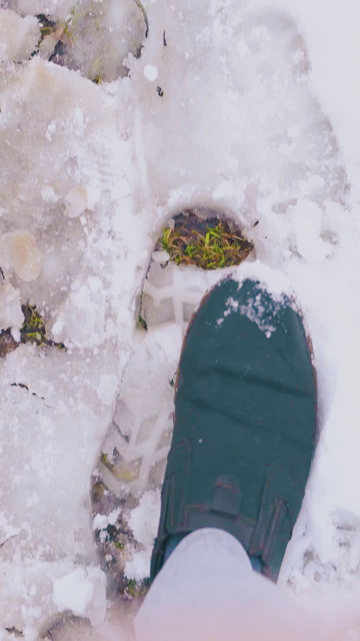 gentleman feet in light grey jeans and dark boots walk fast along clean white snow and sleek on spring day upper view