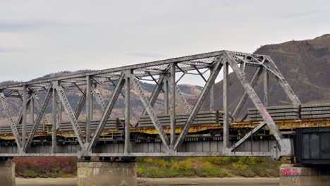 Un-Tren-De-Carga-Que-Cruza-El-Río-South-Thompson-A-Través-Del-Puente-Cnr-Cerca-Del-Parque-Ribereño-Al-Este-Del-Centro-De-Kamloops-En-Un-Día-Nublado-En-Otoño