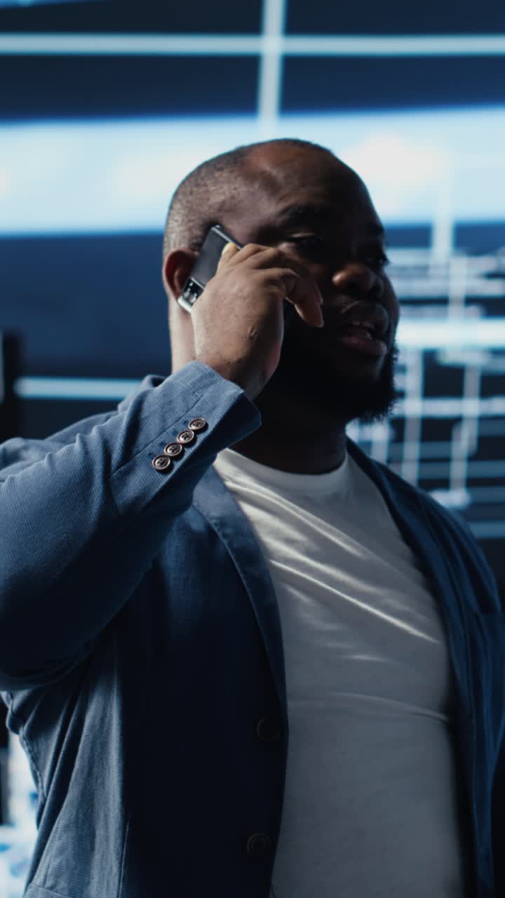 Uomo afroamericano che parla allo smartphone in un ufficio moderno.