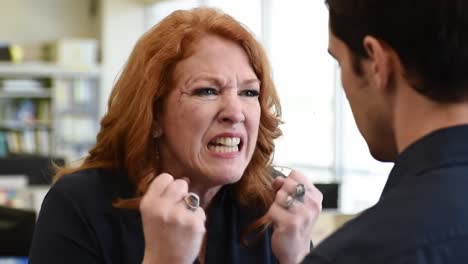 a heated argument unfolds between two individuals in an office environment. emotions run high as they face off, showcasing the difficulties of communication and teamwork in workplace situations.