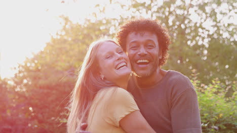 Portrait-Of-Loving-Mature-Couple-Hugging-Outdoors-Against-Flaring-Evening-Sun