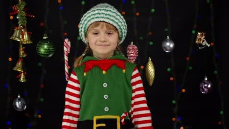 Kid-girl-in-Christmas-elf-Santa-helper-costume-dancing,-fooling-around.-New-Year-holiday-celebration