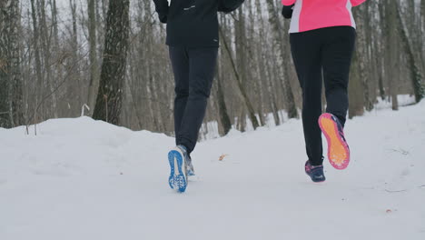 close-up of the feet of two runners in sneakers running in the winter in the park. the married couple goes in for sports.