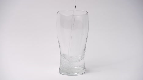 primer plano y cámara lenta de verter agua en un vaso sobre fondo blanco