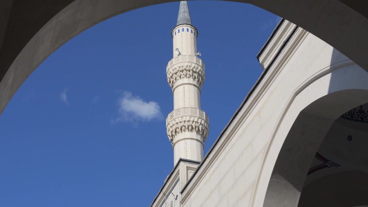 Berrak mavi bir gökyüzünün altında Tiran Ulu Camii'nin uzun minaresini beyaz mermer kemerler çevreliyor.