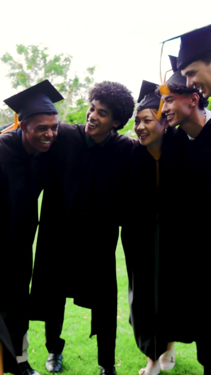 Vertical video: Diverse gowned graduates entering left tapping tassels shaking hands posing on lawn