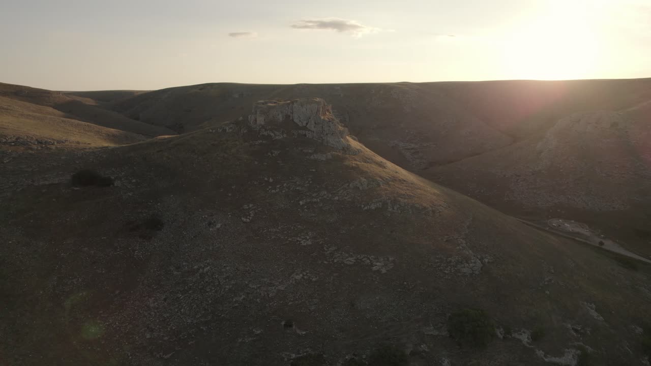 Drone lentää laajassa ympyräliikkeessä vuoren ympärillä auringonnousun aikaan Etelä-Italiassa, 4k-kuvana