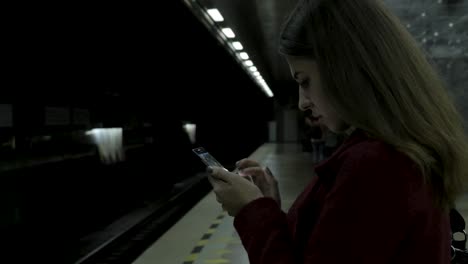 mujer usando un teléfono en una estación de metro