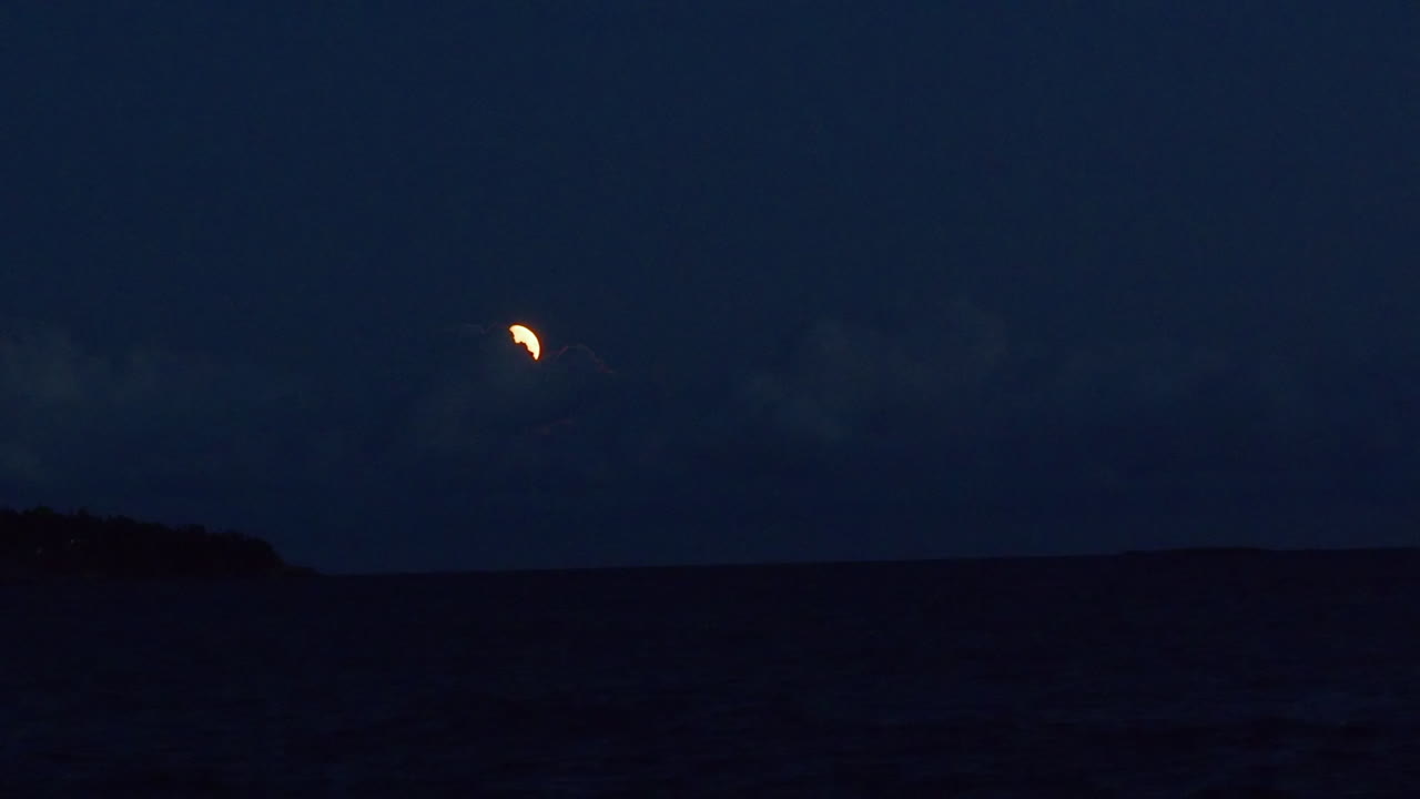 Luna in una notte buia con nuvole che si muovono su di essa.