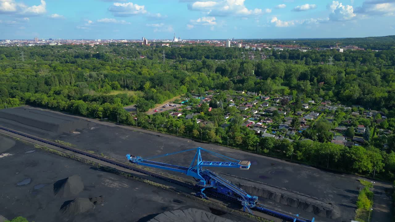 Spreader reclaiming coal Excavator at a coal terminal near residential area. Smooth aerial view flight fly push forward drone