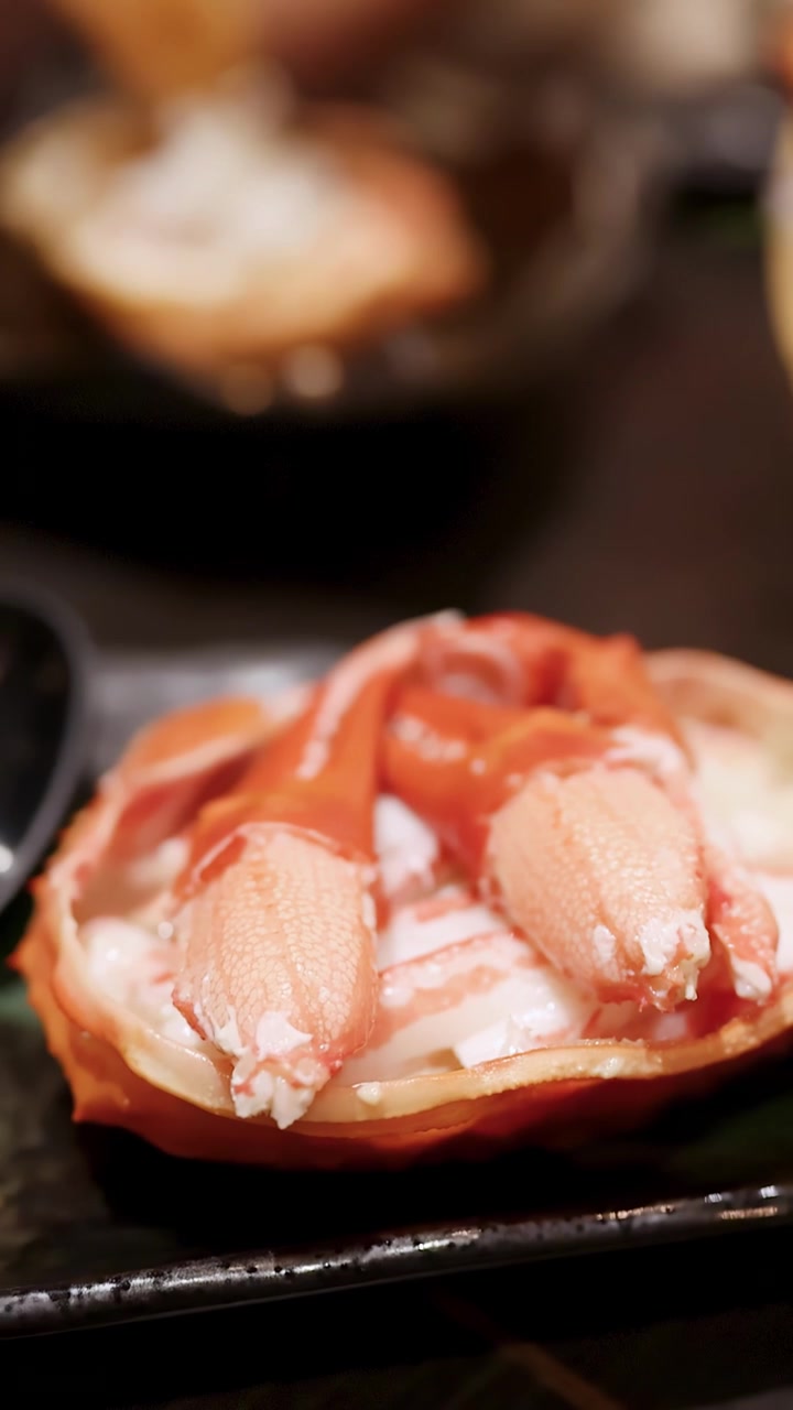 Una ripresa ravvicinata con inclinazione della telecamera rivela fette assortite di pesce crudo e zampe di granchio su una barca di legno