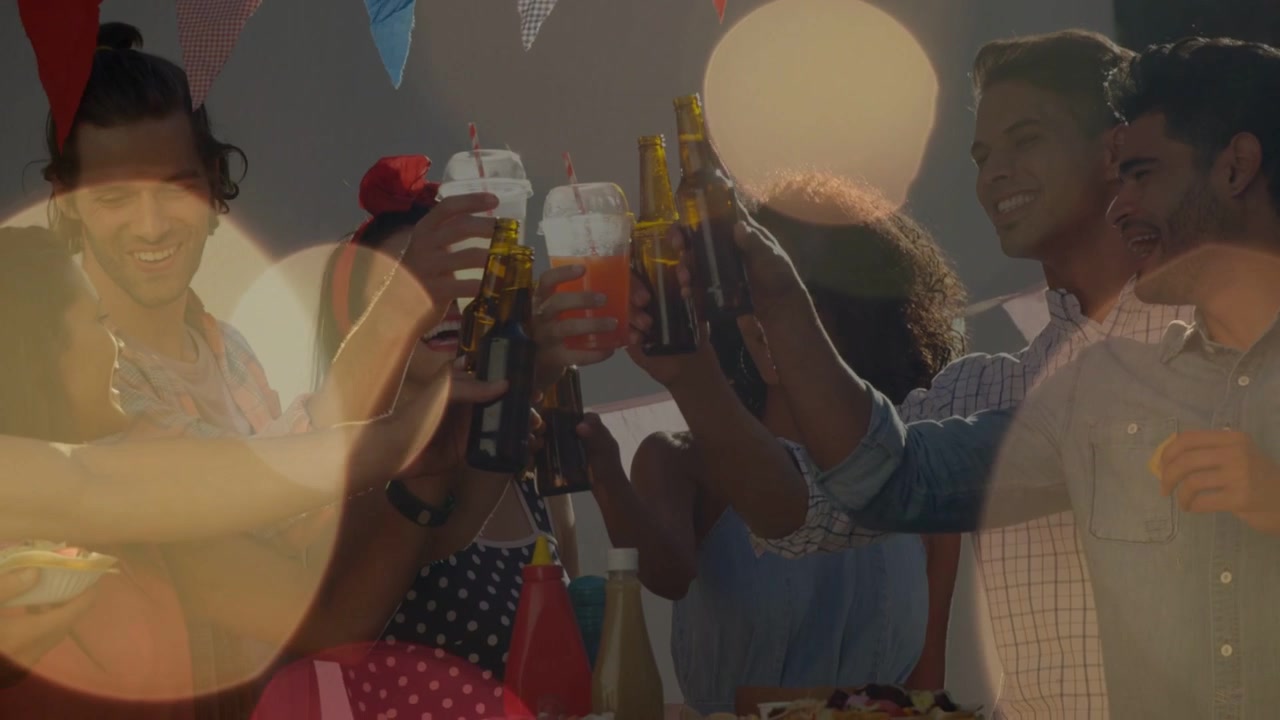 Sei amici che alzano i bicchieri, fanno tintinnare le bottiglie e festeggiano un evento con un effetto bokeh che sfuma i volti.