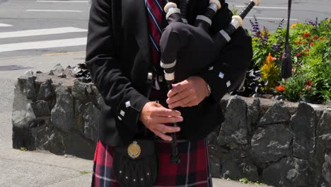 bagpiper playing around the parliament buildings in the summertime in victoria, canada, british columbia.