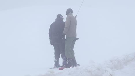 skier and snowboarder on a t-bar lift in a snowy mountain ski resort