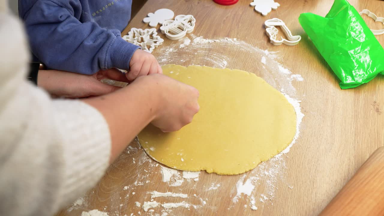 Close-up shot of child and parent using cookie cutters on dough. Fun, engaging kitchen activity with flour and cutters on a wooden surface. Bright, natural lighting enhances the joyful mood