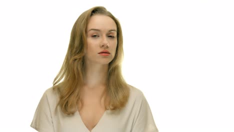 A-close-up-of-a-woman-looking-off-into-the-distance,-then-turning-her-head-to-face-the-camera,-on-a-seamless-white-studio-background