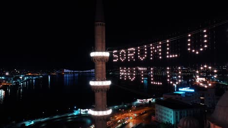 vista aérea nocturna de la nueva mezquita. dice "sea responsable, sea feliz"