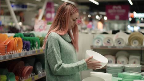 woman shopping tableware, choosing plates in supermarket