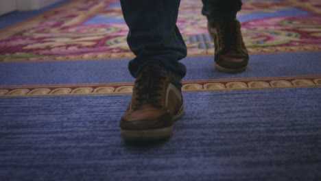 male feet in sport shoes walking on carpet floor in corridor guest hotel