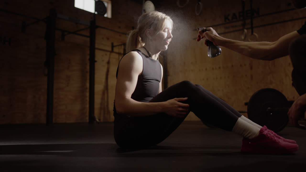 금발 여성 인플루언서가 체육관 피트니스 촬영 중에 물 병으로 스프레이됩니다.